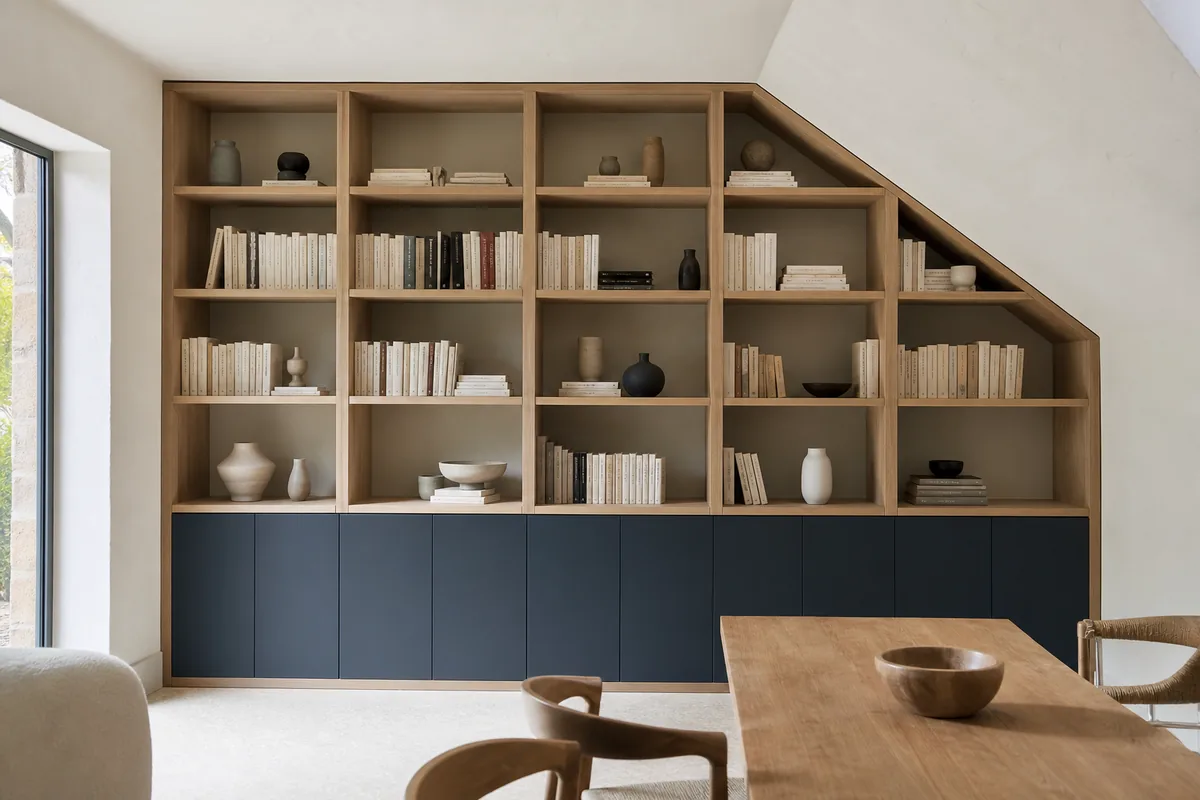 Bibliothèque toute hauteur en bois clair adossée à un mur blanc dans un séjour de maison vendéenne